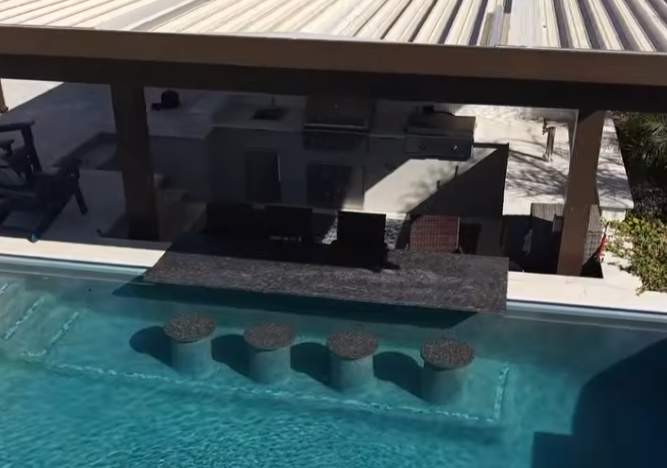 Outdoor bar with granite counter built at the edge of an Arizona pool with submerged stools